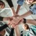 Image of young colleagues in office holding hands of each other. Looking aside.